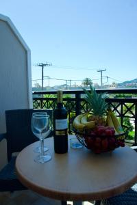 a bottle of wine and a bowl of fruit on a table at Johnhara Studios & Apartments in Ialysos
