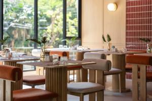 a restaurant with tables and chairs and windows at The Akyra Bangkok 11 in Bangkok