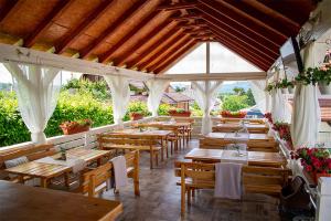 a restaurant with wooden tables and white curtains at Pensiunea Mariana in Ocna Şugatag