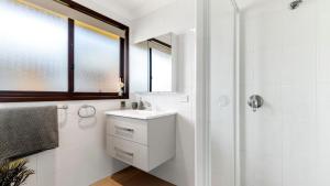 a white bathroom with a sink and a shower at Watersedge in Currarong