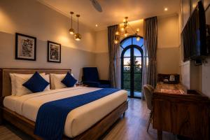 a bedroom with a bed and a desk and a window at The Belmonte House by Noventa - Rooftop Pool Hotel in Udaipur in Udaipur +42 photos
