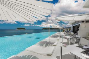 a pool on a cruise ship with white lounge chairs and the ocean at Kata Rocks in Kata Beach