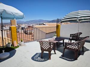 a patio with two chairs and a table and an umbrella at Judería Suite Jaén in Jaén