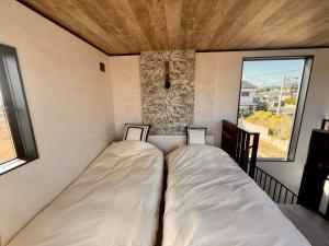 two beds in a small room with a window at Calme Villa in Asahi