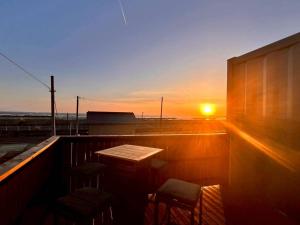 a sunset on a balcony with a table and chairs at Calme Villa in Asahi +35 photos