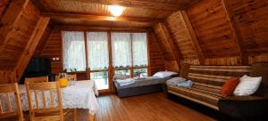 a living room with a couch and a bed and a window at Osada Kujanki - domek wakacyjny in Zakrzewo