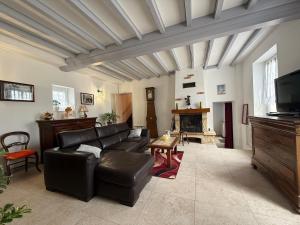 a living room with a black leather couch and a fireplace at La ferme des Gabelles in Saint-Benoît-sur-Loire