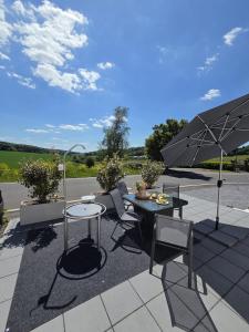 a patio with a table and an umbrella at Ferienhaus Eifel Horizont in Neuheilenbach