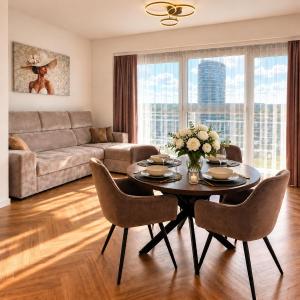 a living room with a table and chairs and a couch at Olszynki Park Elite Residence in Rzeszów