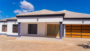 a white house with brown doors and a brick driveway at Hillview Executive Self-Catering House in Blantyre