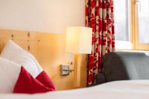 a room with a bed with a lamp and a couch at Hotel Garni Frommes in Fiss
