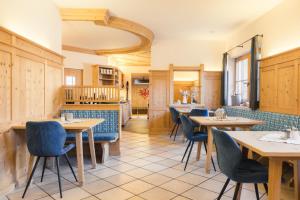 a restaurant with wooden tables and blue chairs at Hotel Garni Frommes in Fiss