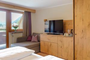 a hotel room with a bed and a tv and a couch at Boutiquehotel Acherl in Achenkirch