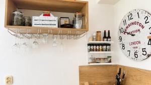 a clock on a wall next to a shelf with wine glasses at Domček u Kubáňov in Bešeňová +7 photos
