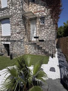 a stone building with a window and palm trees in front of it at Jungle Room avec jacuzzi privé, rétro-projecteur, jardin & terrain de pétanque in Saint-Yzan-de-Soudiac