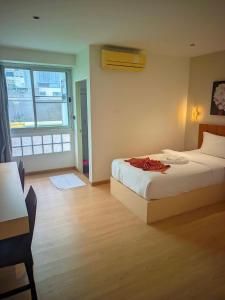 a bedroom with a bed and a table and a window at Hotel Soni Mansion Pratunam in Bangkok