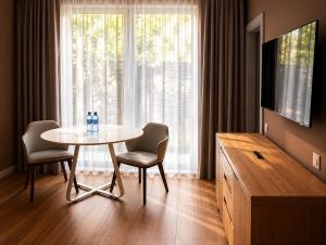 a living room with a table and chairs and a television at Syndicate Lodging Aparthotel in Cluj-Napoca