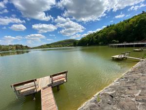two benches sitting on a dock on a lake at Leveleki Eszter Üdülő in Bánk