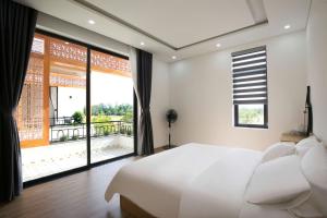 a bedroom with a large bed and a large window at Cloud Rose Villa Hoi An in Danang