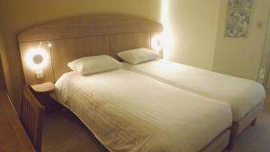 a bedroom with a large white bed with two pillows at The Originals City, Hôtel Le Gayant, Douai in Douai
