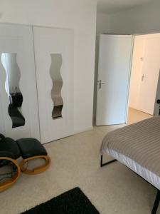 a bedroom with a bed and a chair and doors at Ma maison in Bonneuil-Matours