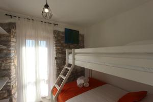 a bedroom with a bunk bed with a ladder and a window at Stone Villa with sea view and pool in Smokvica