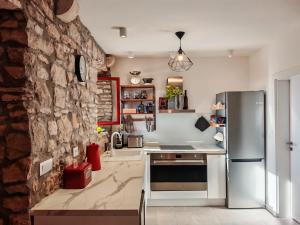 a kitchen with a stone wall and a refrigerator at Stone Villa with sea view and pool in Smokvica