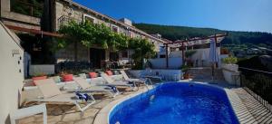a hotel with a swimming pool and chairs next to a building at Stone Villa with sea view and pool in Smokvica