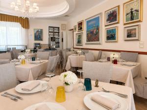 a restaurant with tables and chairs with white table settings at Hotel Da Mario in Caorle