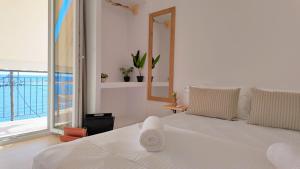 a white bedroom with a large bed and a window at To Nisaki in Loutraki