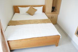 a bed in a small room with white sheets and pillows at Morgan Hotel in Ấp Bình Hưng