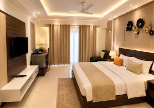 a bedroom with a large bed and a television at Joygaon Hotel & Resorts in Jhajjar +27 photos