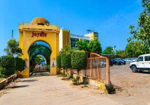 a yellow building with a gate in a parking lot at Joygaon Hotel & Resorts in Jhajjar
