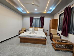 a bedroom with a bed and two chairs at Hotel Pooja Inn Pandharpur in Pandharpur +9 photos