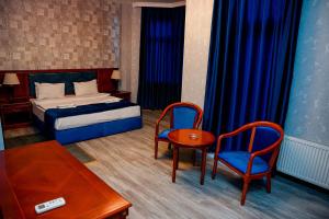 a bedroom with a bed and two chairs and a table at Khazri Resort & Villas in Baku
