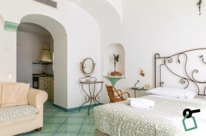a bedroom with a bed and a couch and a chair at Hotiday Positano Suites and View in Positano