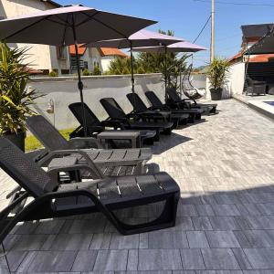a row of lounge chairs and umbrellas on a patio at Villa Ronić in Soko Banja