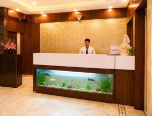 a man standing behind a counter with a fish tank at Hotel Sunbeam in Gwalior