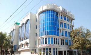 a large building with blue windows on a street at Hotel Sunbeam in Gwalior