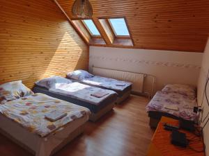 a room with three beds and a ceiling with windows at Leveleki Eszter Üdülő in Bánk