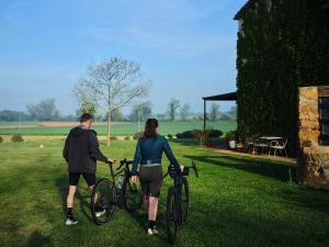 a man and a woman holding bikes in the grass at Can Serrà 1786 in Llagostera