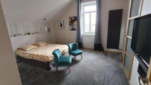 a bedroom with a bed and two green chairs at Pierres et souvenirs in Usson-en-Forez