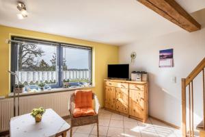 a living room with a tv and a table and a window at Ferienwohnungen zur Eule - Steinkauz in Clausdorf
