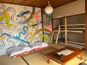 a room with a mural on the wall with a bed and a table at Bakushuku Den Guest House Brew in Matsuyama +87 photos