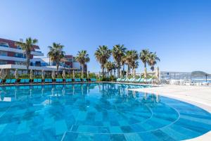a large swimming pool with palm trees and a beach at Azure By Yelken Hotel in Turgutreis