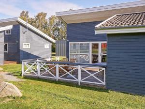 a house with a porch with a wooden fence at Danland Rø Golf Houses in Gudhjem