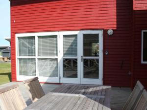 a red house with a patio with a door and two chairs at Danland Rø Golf Houses in Gudhjem +67 photos