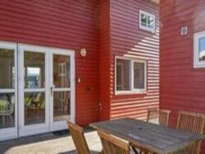 a wooden table in front of a red building at Danland Rø Golf Houses in Gudhjem