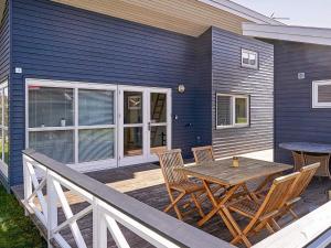 a blue house with a wooden table and chairs on a deck at Danland Rø Golf Houses in Gudhjem