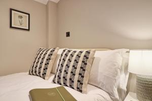 a bed with white pillows and a green book on it at Noble Goose Rooms in Coggeshall
